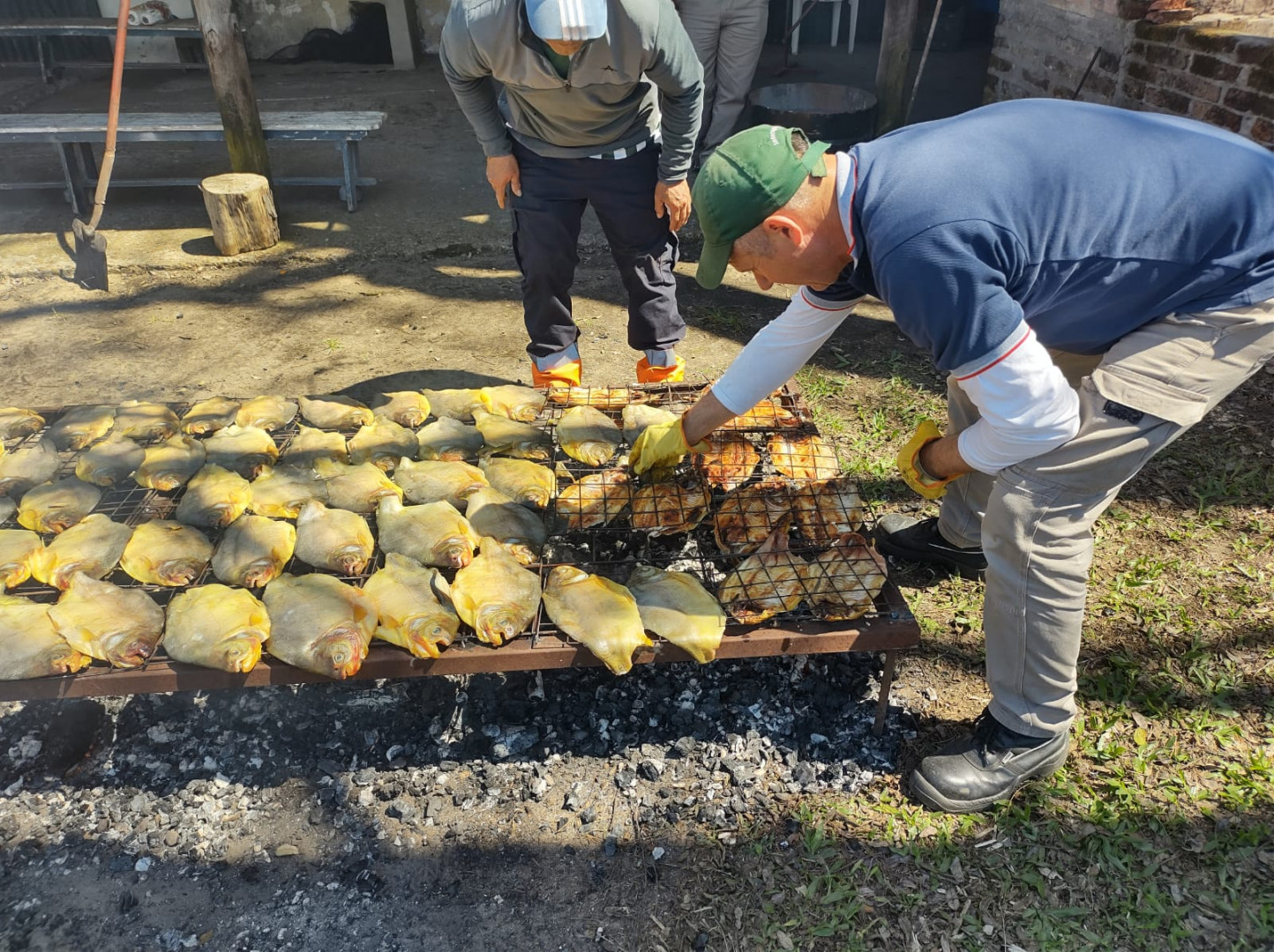 Una persona manipula una parrilla con pescados durante una actividad difundida por INTA Concordia.